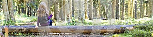 Young girl with long hair sitting on a tree log in autumn forest