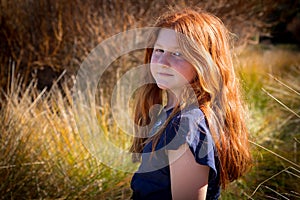 Young girl with long red hair against an autumnal natural background