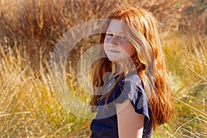 Young girl with long red hair against an autumnal natural background