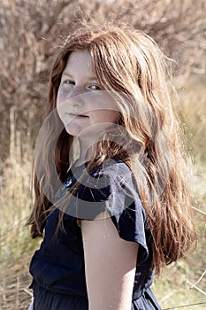 Young girl with long red hair against an autumnal natural background