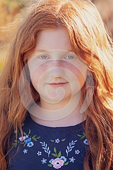 Young girl with long red hair against an autumnal natural background