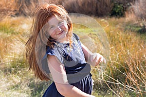 Young girl with long red hair against an autumnal natural background
