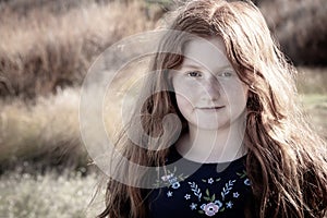 Young girl with long red hair against an autumnal natural background