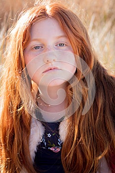 Young girl with long red hair against an autumnal natural background