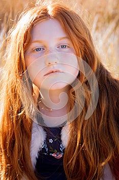 Young girl with long red hair against an autumnal natural background