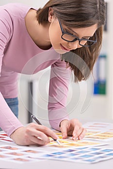 Young girl is looking through color print-outs. photo