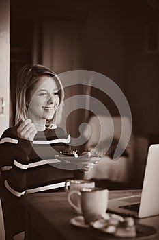 Young girl looking at computer and eating