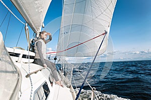 Young girl looking forward sitting on yacht desk having trip