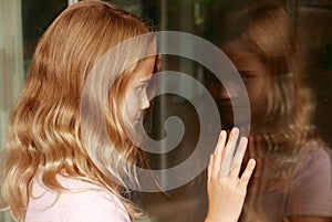 Young girl looking at her reflection in a window