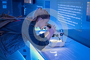 girl looking through microscope in science lab photo