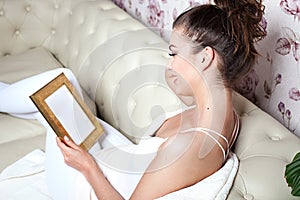 Young girl looking at photoframe.