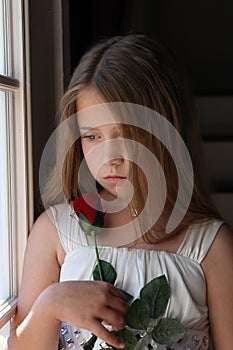 Young girl looking at rose