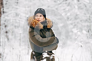Young girl looking at side on background of snowy trees on walk in winter forest
