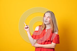 Young girl looking sideways and pointing her index finger at copy space your text or promotional content