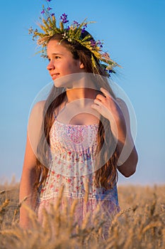 Young girl looking to sunset on wheat field