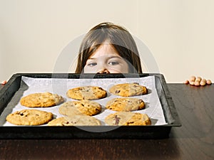 Young girl looking at a tray of fresh baked cookies