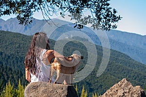 Young girl looks at the landscape with her dog