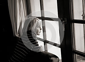 A young girl looks out the window. She has a serious look on he