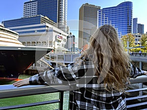 A young girl looks at the sea on a huge cruise liner that is sailing off the coast of Canada Place Center Vancouver and