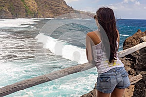 Young girl looks at the sea from the point of view of the beach of Nogales