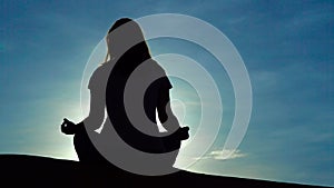 Young girl in a lotus pose meets the dawn in the red desert