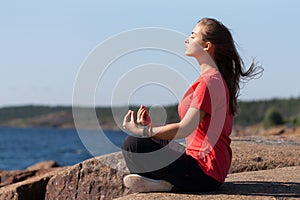 Young girl in lotus pose on the rocks