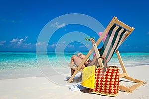 Young girl lying on a beach lounger with glasses in hand on the