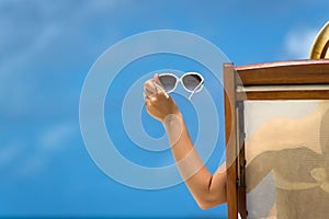 Young girl lying on a beach lounger with glasses in hand on the tropical island