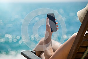 Young girl lying on a beach lounger with mobile phone in hand on