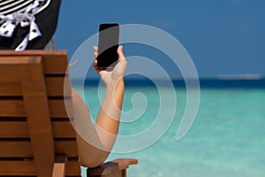 Young girl lying on a beach lounger with mobile phone in hand on