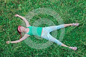 Young girl lying on bright green grass with outstretch