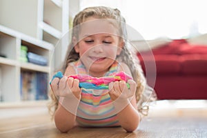 Young Girl Lying On Floor Playing With Colorful Slime