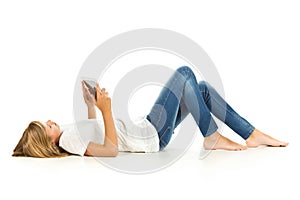Young girl lying on the floor using tablet pc over white background