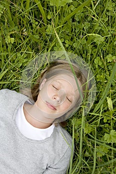 Young girl lying in the grass dreaming of ...