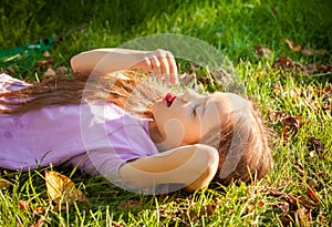 Young girl lying on grass and eating cherry outdoor