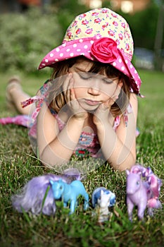 Young girl lying on grass, holding head in hands