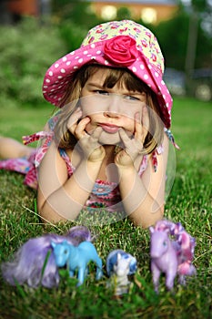 Young girl lying on grass, holding head in hands