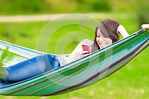 Young girl lying on a hammock with cell phone