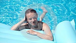 Young girl lying on a mattress in the pool