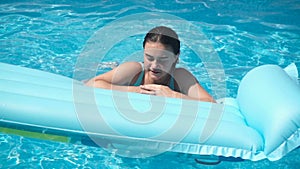 Young girl lying on a mattress in the pool