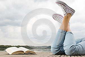 Young girl lying on a pier next a book