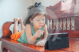 Young Girl lying on wooden stool and Learning online course on Wireless Digital Tablet