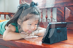 Young Girl lying on wooden stool and Learning online course on Wireless Digital Tablet