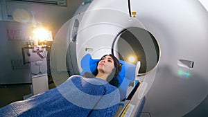 Young girl on a magnetic resonance imaging MRI scanner in a modern hospital.