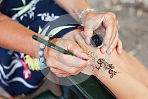 young girl make a temporary tattoo of mehendi from henna on hand