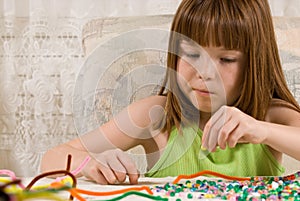 Young girl making bead bracelets