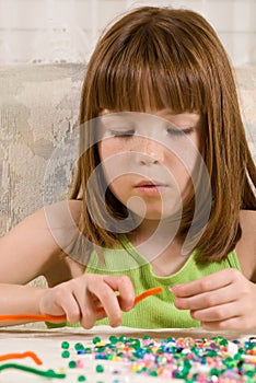 Young girl making bead bracelets