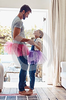Young girl on man feet, ballet dancing and fun with learning at home in tutu, bond with love and creativity. Family