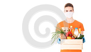 Young girl in a mask and an orange t-shirt holds a wooden box with groceries for delivery isolated on white background