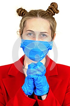 A young girl in a medical protective mask and latex gloves prays faithfully to God. She& x27;s wearing a red coat. Warning